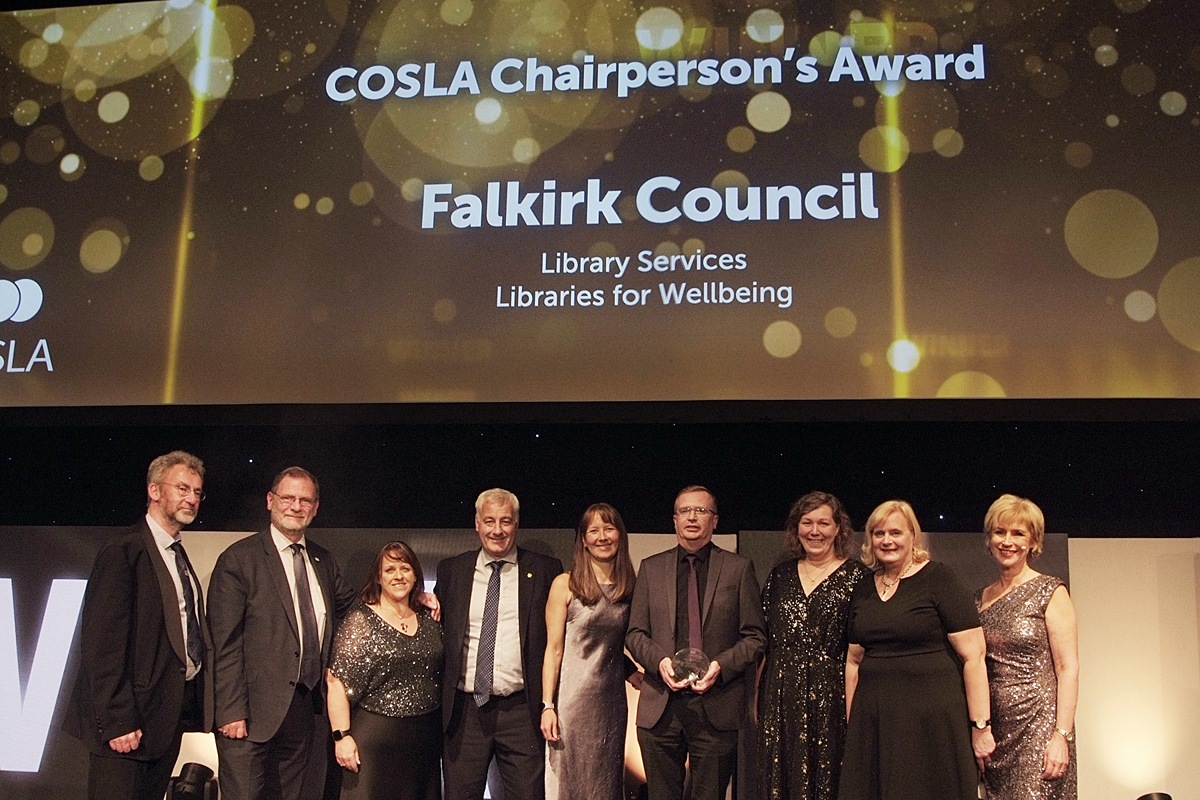 A photograph of people smiling while collecting an award on stage.