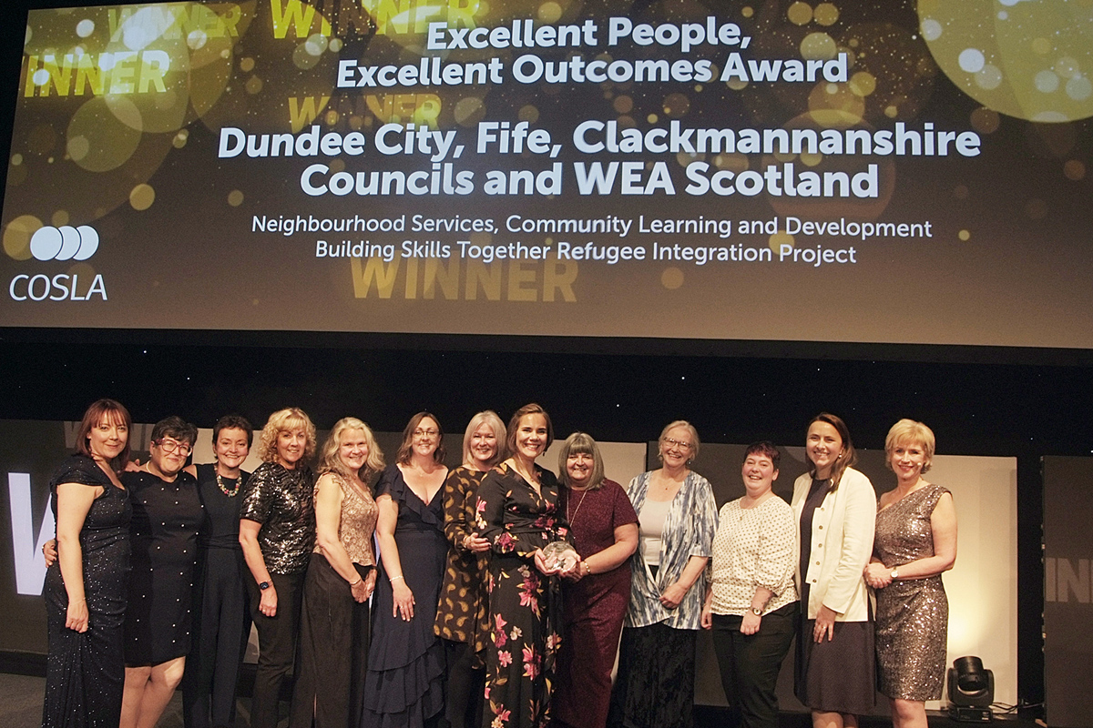 A group of people smiling, collecting an award on stage.