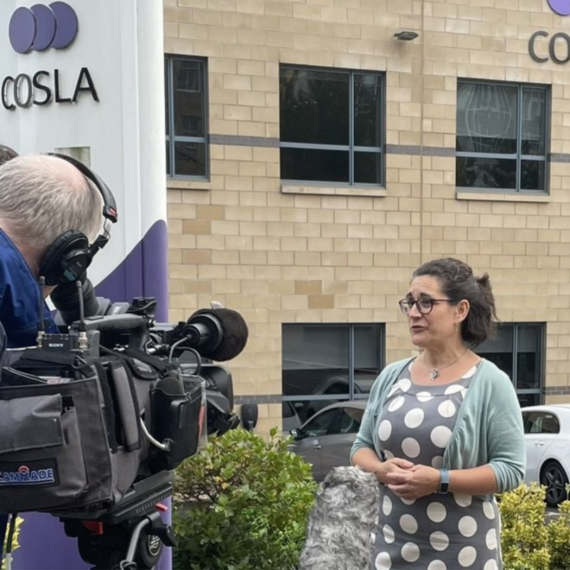 A person being interviewed with a TV camera filming.