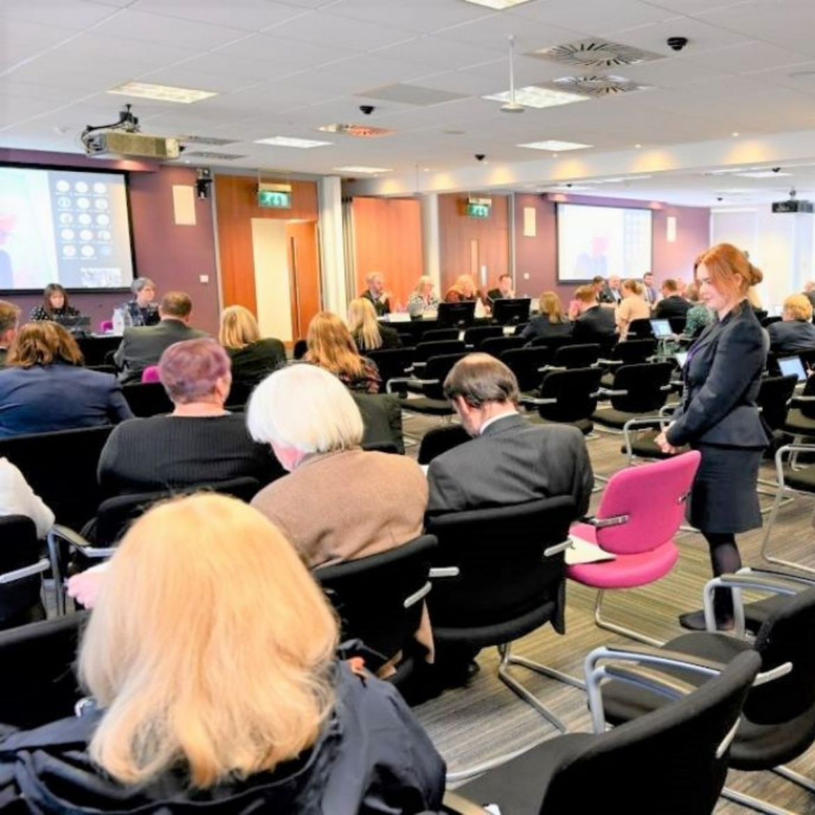 People sitting and standing at a conference.